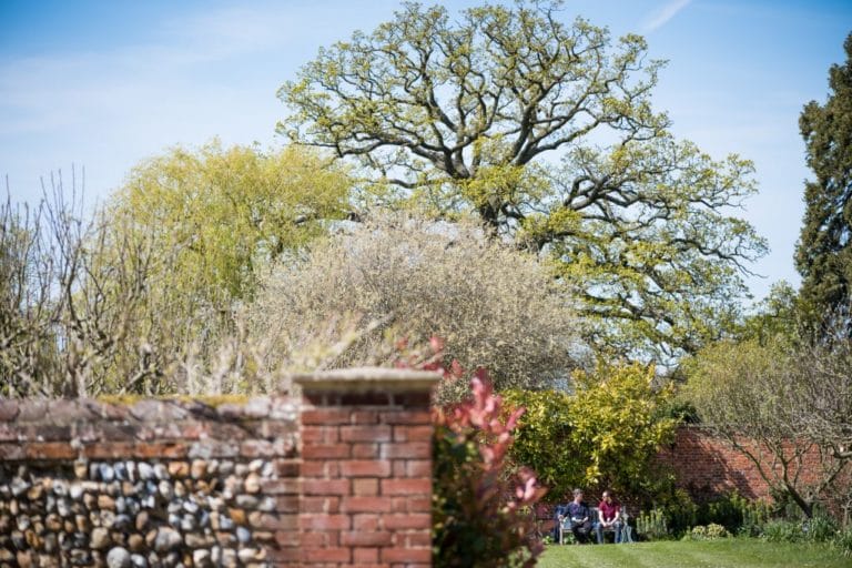 Image of two people chatting on bench in the orchard