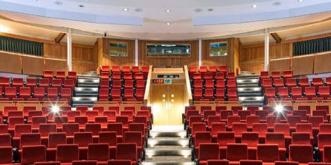 Francis Crick Auditorium, looking towards the technicians booth. Bright read matt seats, and lights gleaming.