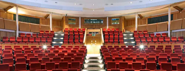 Francis Crick Auditorium, looking towards the technicians booth. Bright read matt seats, and lights gleaming.