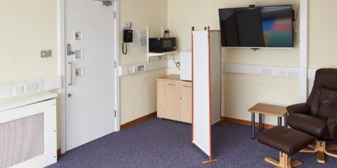 The Family Room at Hinxton Hall Conference Centre, showing comfortable seating, a padded play area, microwave, fridge, highchair, and a screen