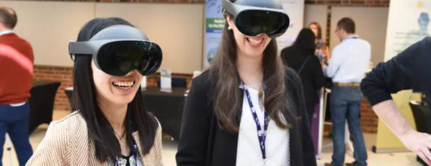 Two smiling, female delegates wearing VR headsets at Cam Tech Week