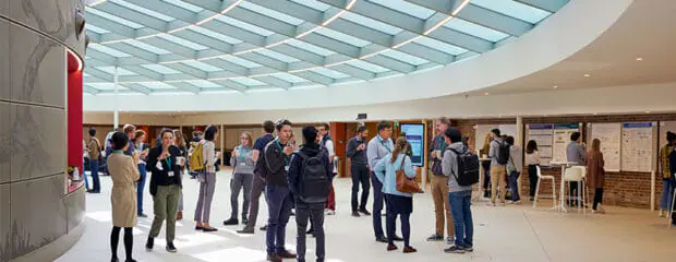 Conference delegates enjoying networking time during break in the Event Space. Above them is a glass and steel roof letting in light.