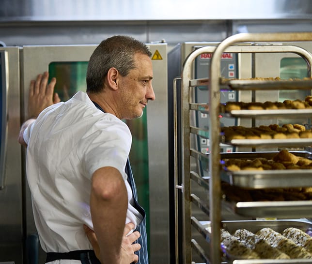 Onesto Iommelli standing by oven with rack of trays to his right